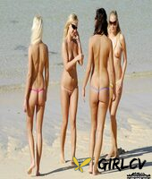 four girls model revealing bikini bottoms while topless on a sandy beach