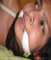 dark-haired girl is cleave gagged and hogtied on a bed in a dress6329